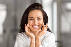 A woman touching her cheek and admiring the results of a chemical peel in Frisco, TX